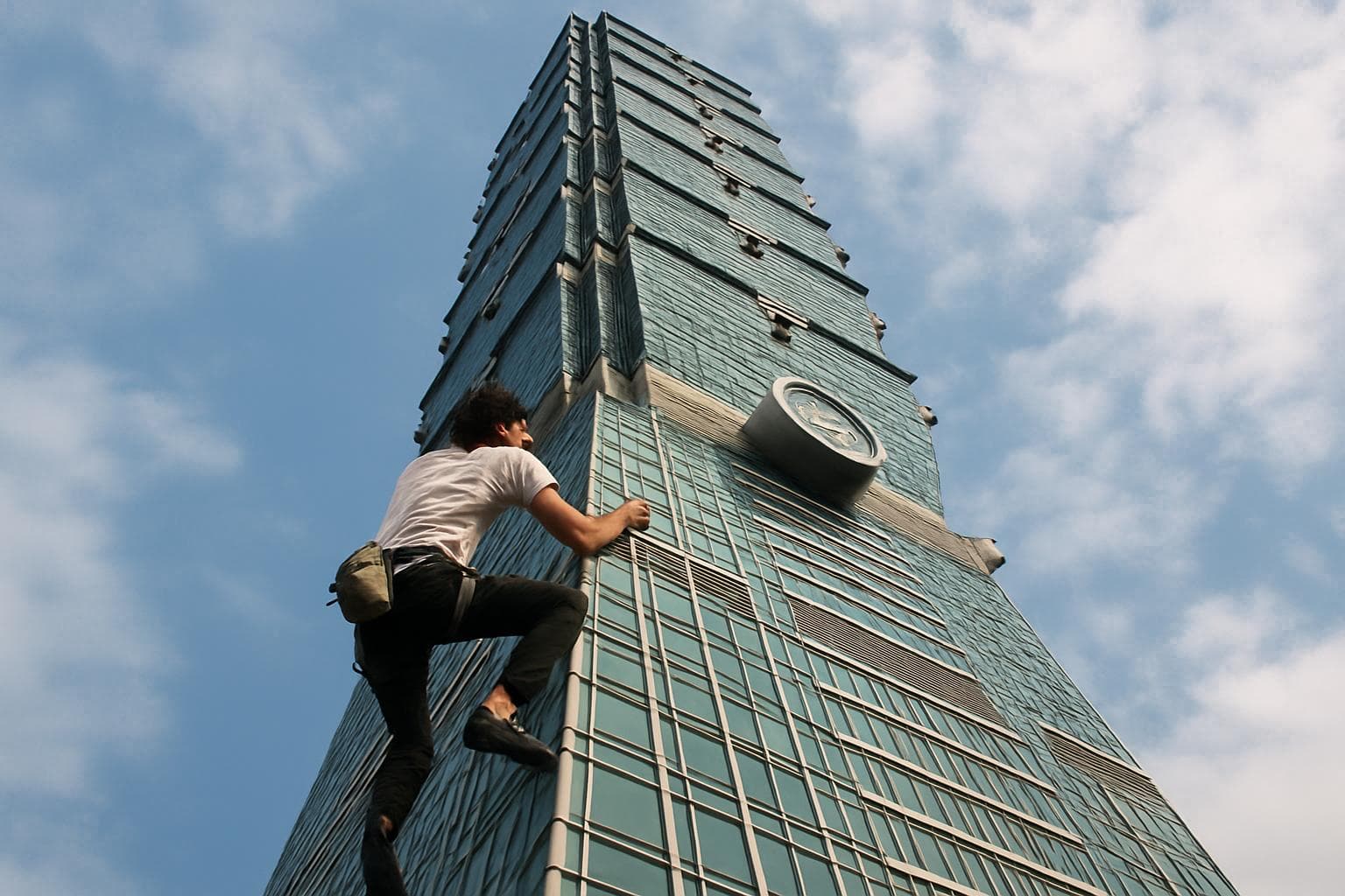 Climber scaling Taipei 101 skyscraper without ropes